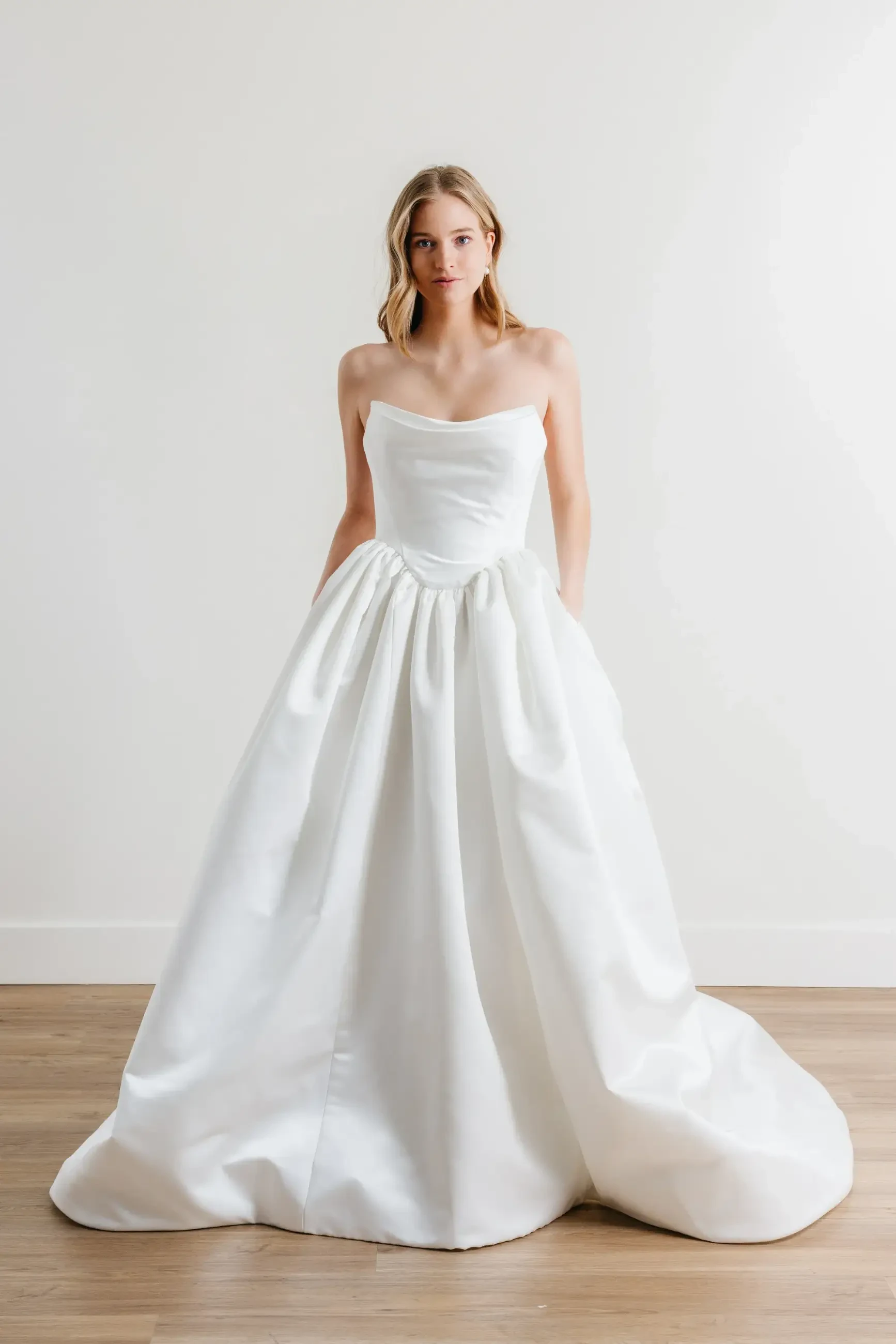 model is wearing a strapless satin ball gown wedding dress