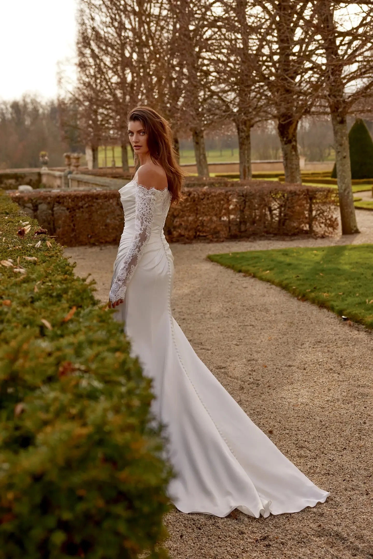 model is wearing a sleek off the shoulder lace wedding dress