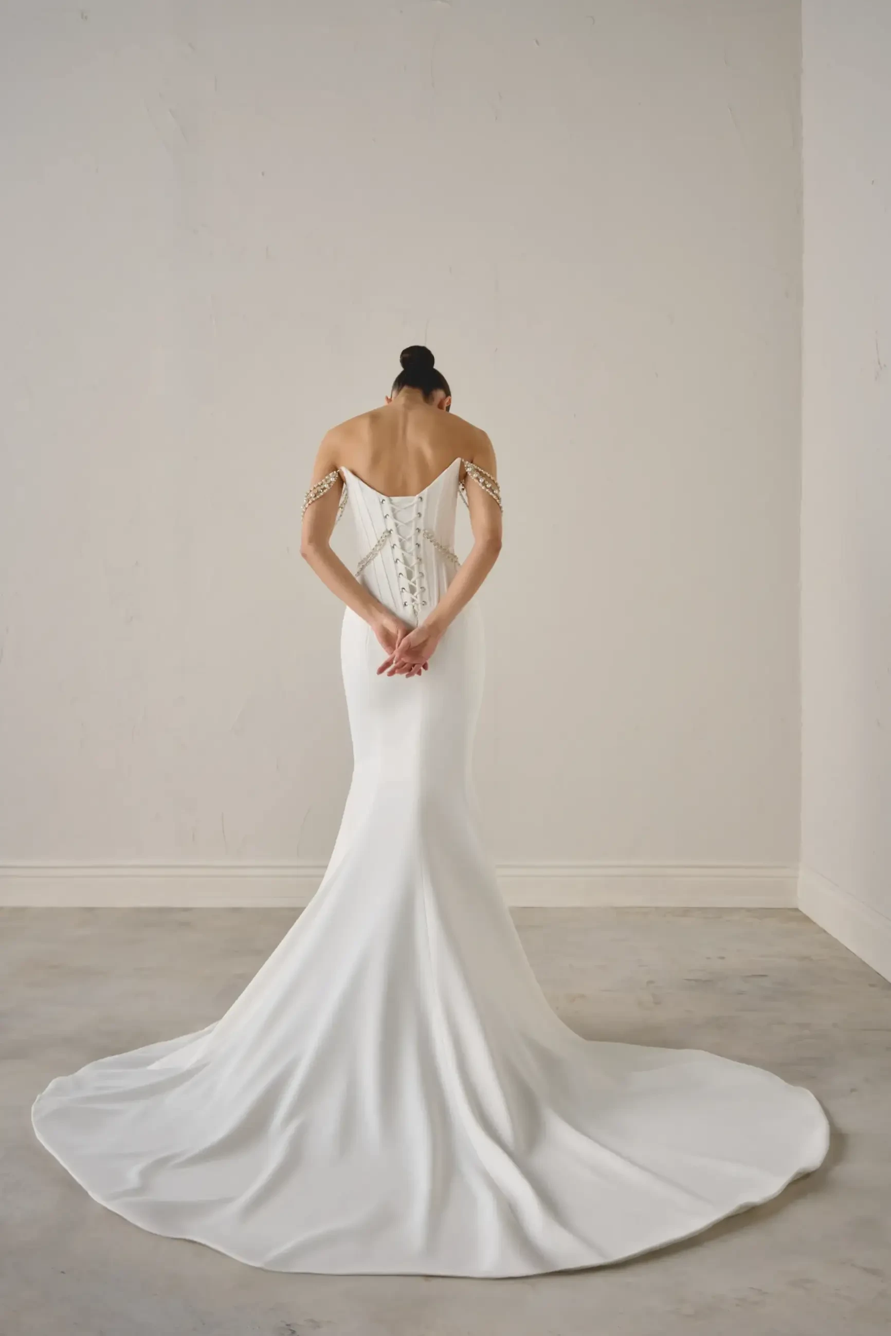 Model is wearing a matte satin fit and flare bridal gown with draped beading and corset boning 