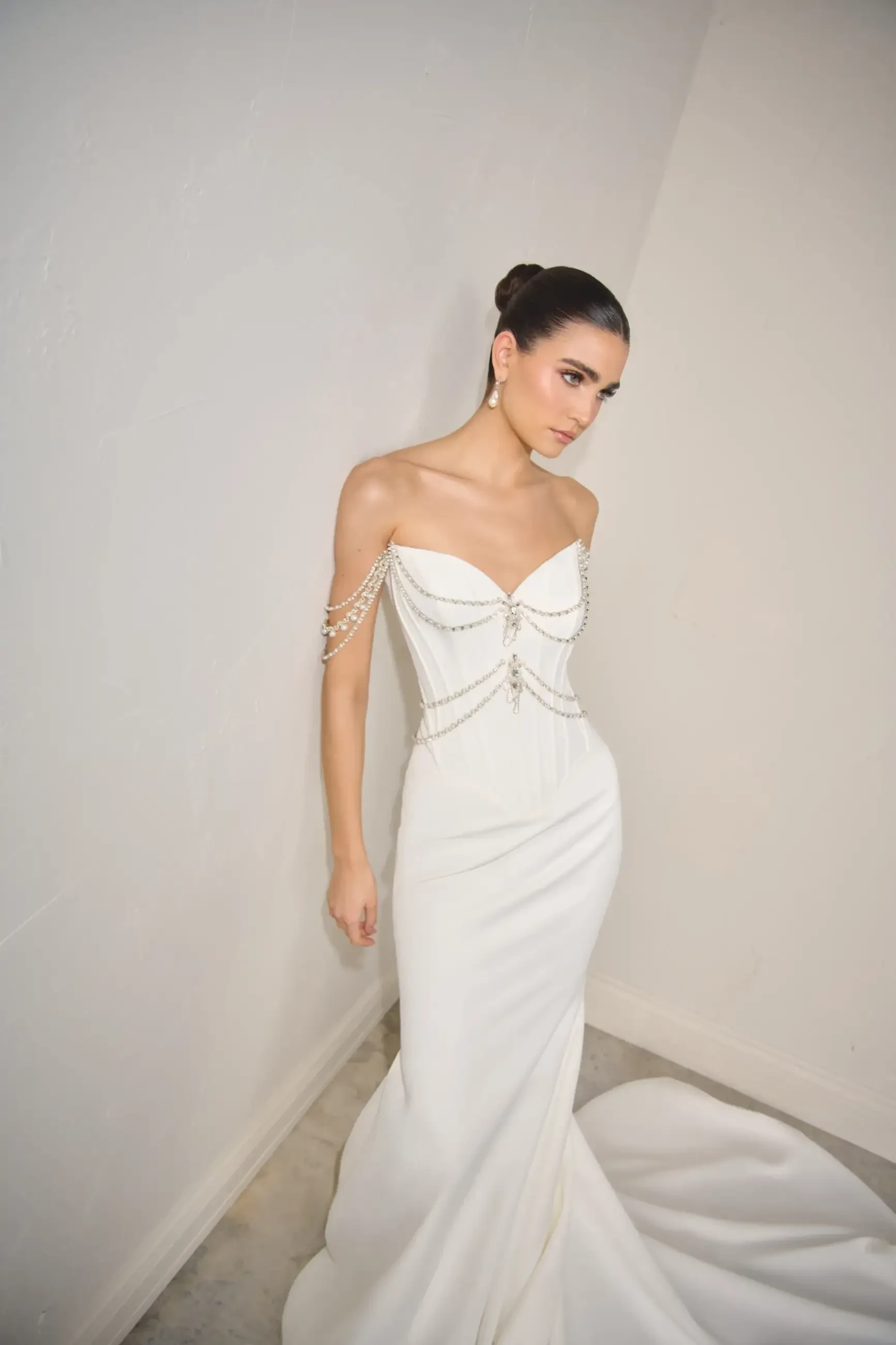Model is wearing a matte satin fit and flare bridal gown with draped beading and corset boning 