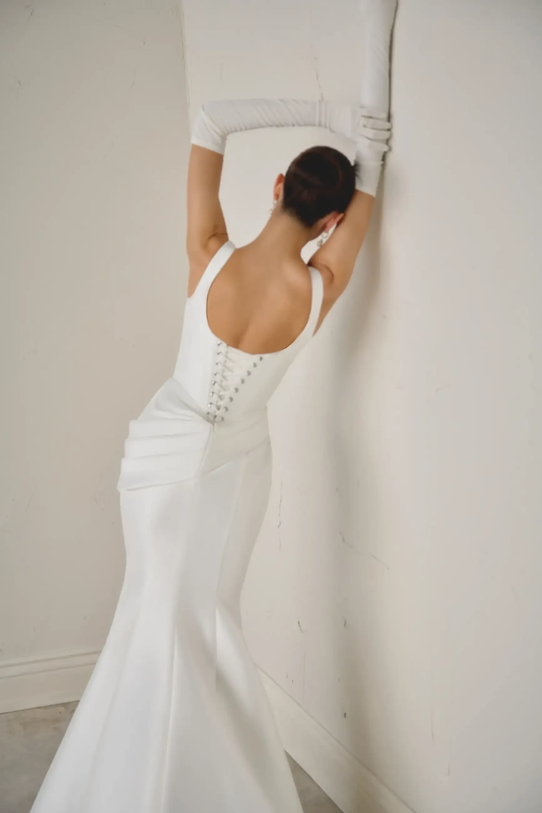 Model is wearing a mikado fit and flare bridal gown with a basque waist 