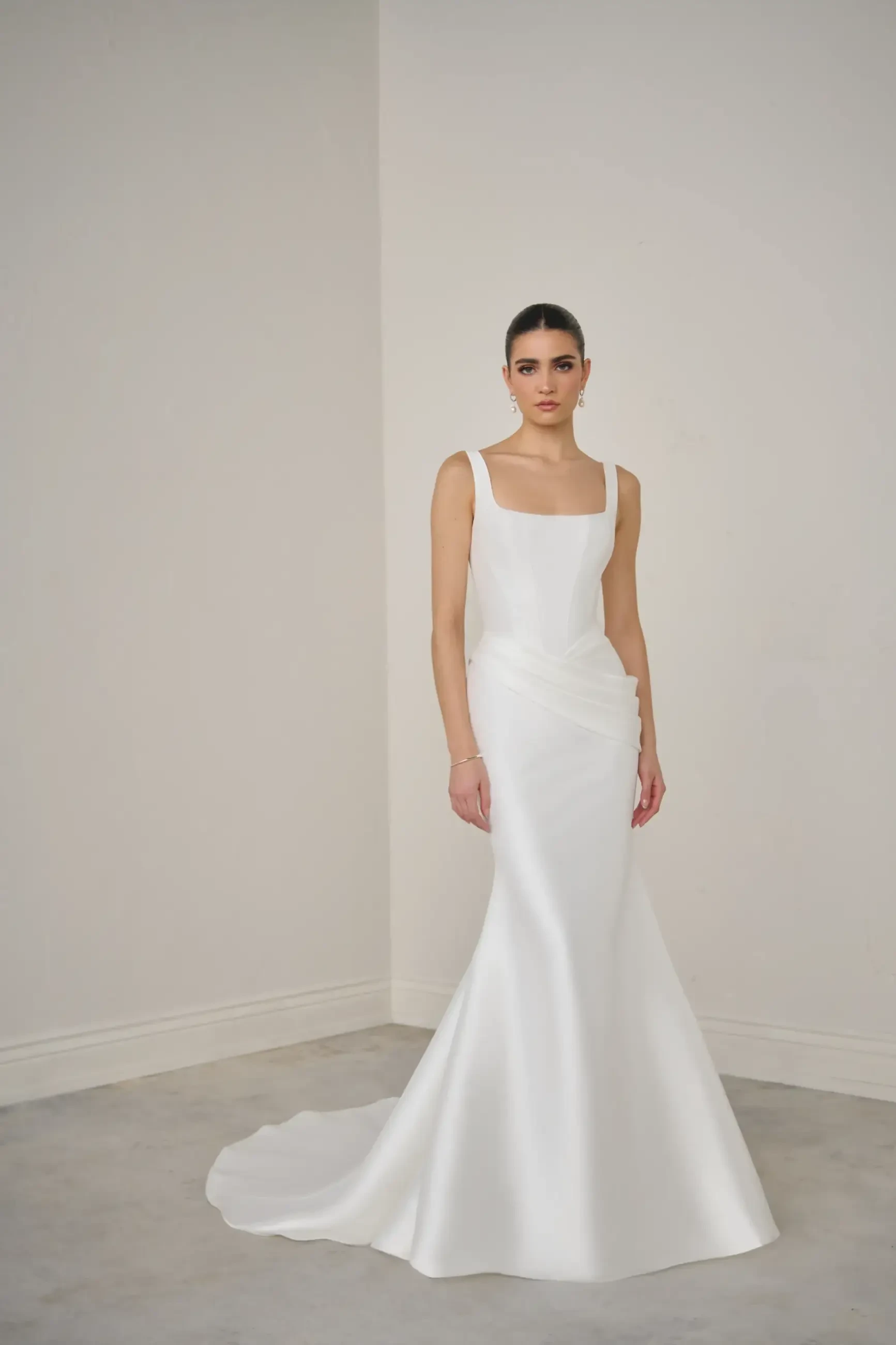Model is wearing a mikado fit and flare bridal gown with a basque waist 