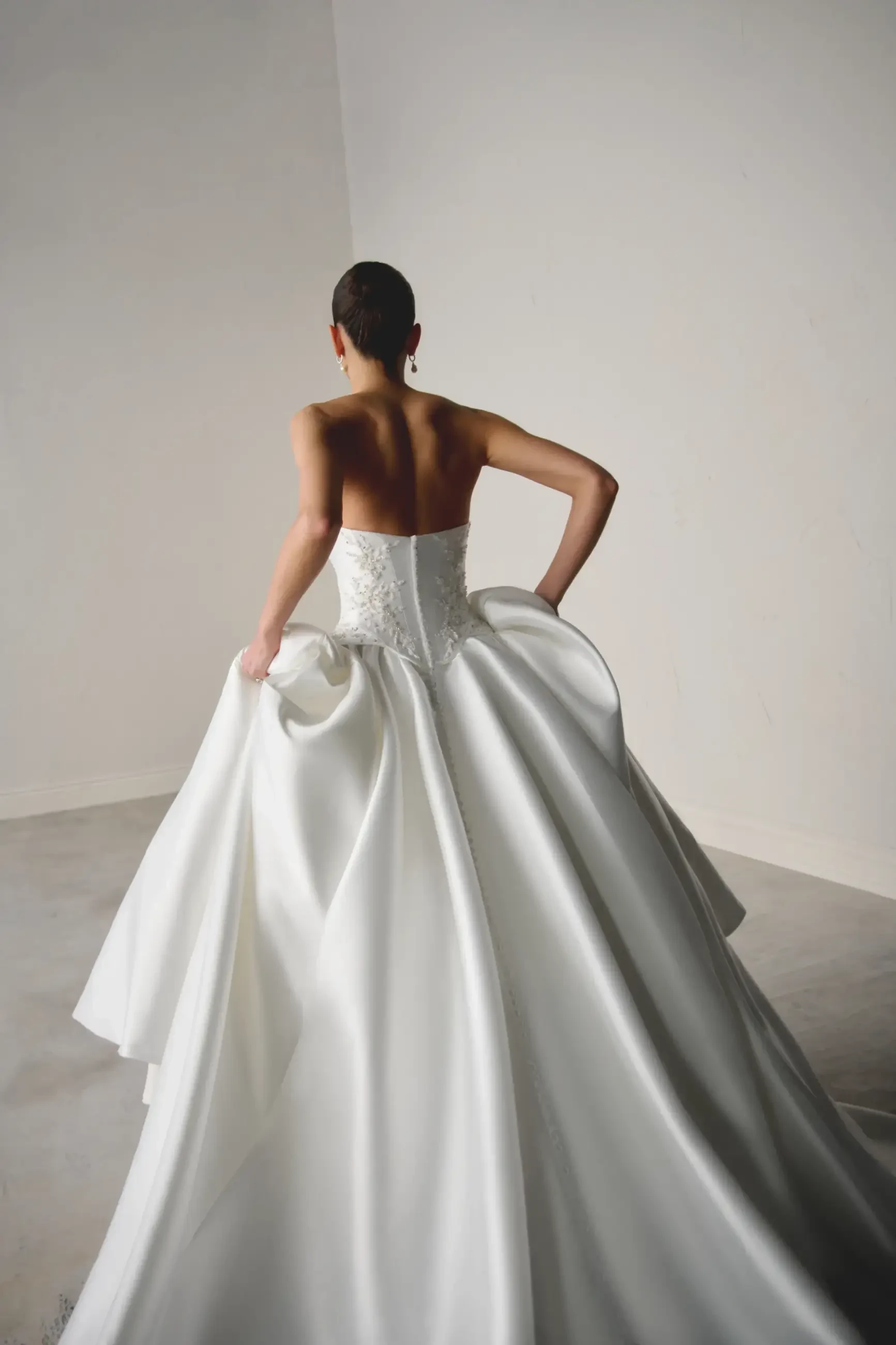 Model is wearing a mikado ball gown with a beaded corset bodice and basque waist