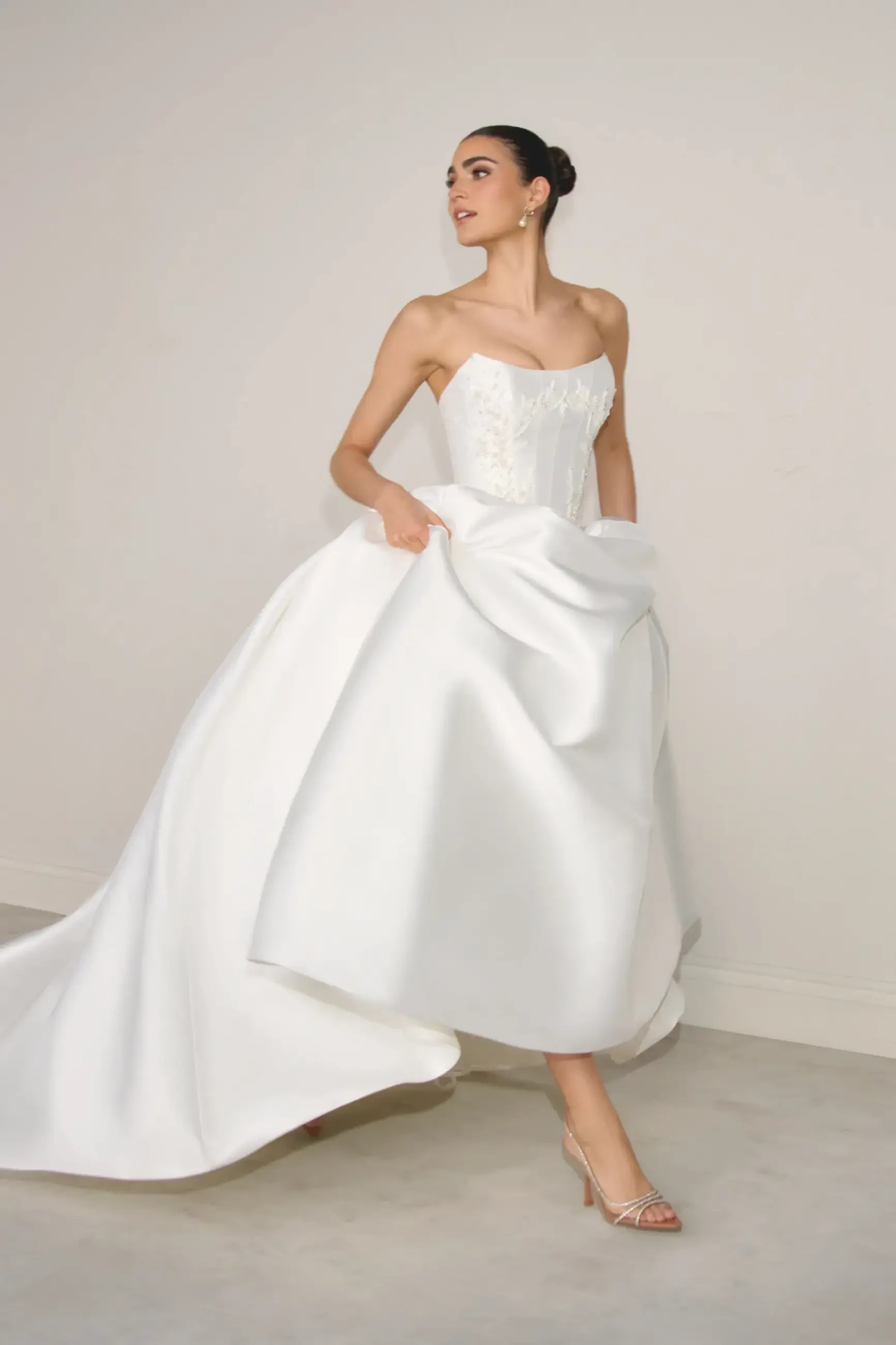 Model is wearing a mikado ball gown with a beaded corset bodice and basque waist