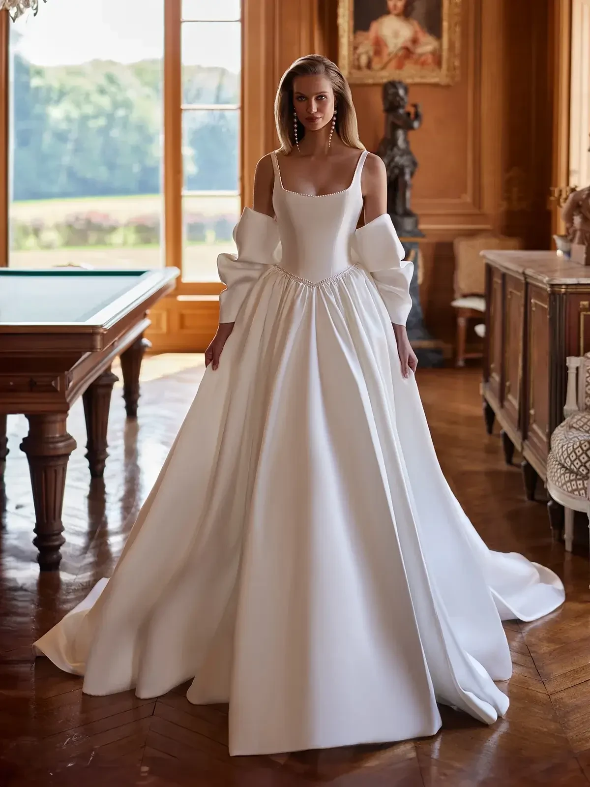 model is wearing a sleeveless satin ball gown wedding dress with a dropped waist