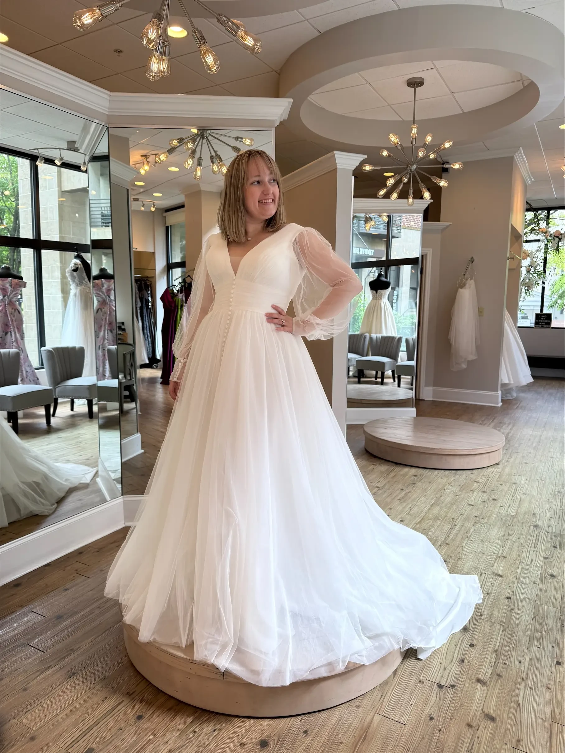 Model is wearing a long sleeve ball gown wedding dress with a v-neckline and sheer long sleeves