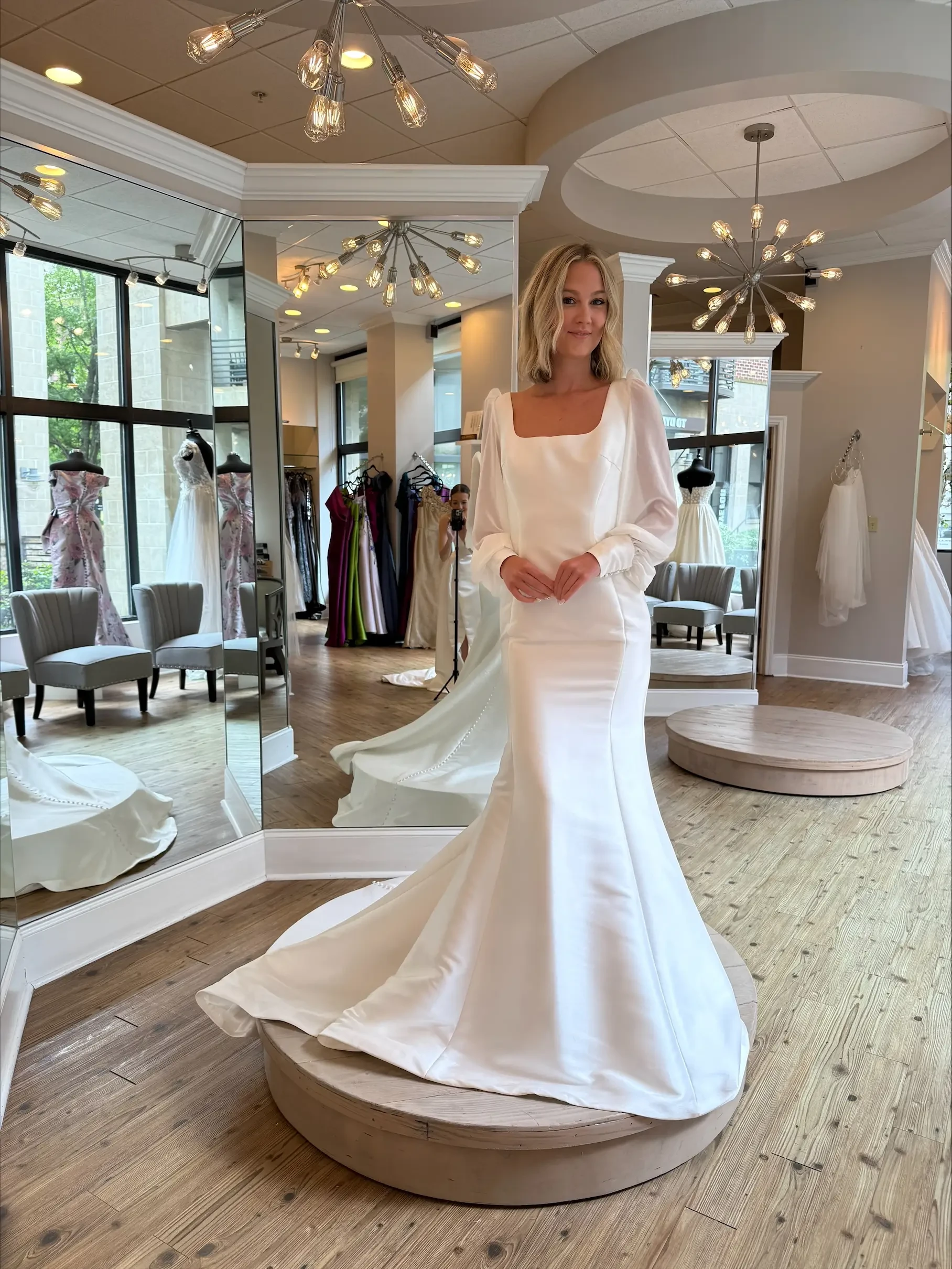 Model is wearing a long sleeve mermaid bridal gown with a square neckline 
