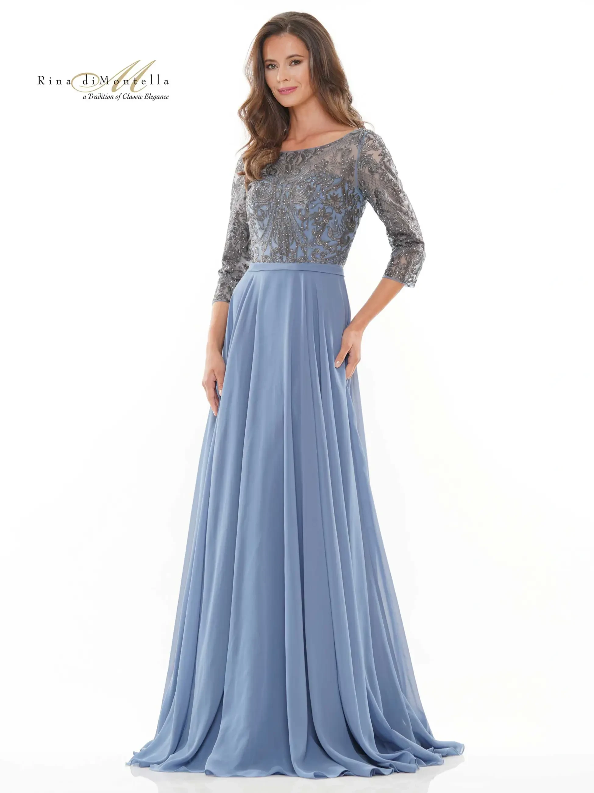 A woman in a long, flowing blue dress with silver embellished sleeves standing elegantly.