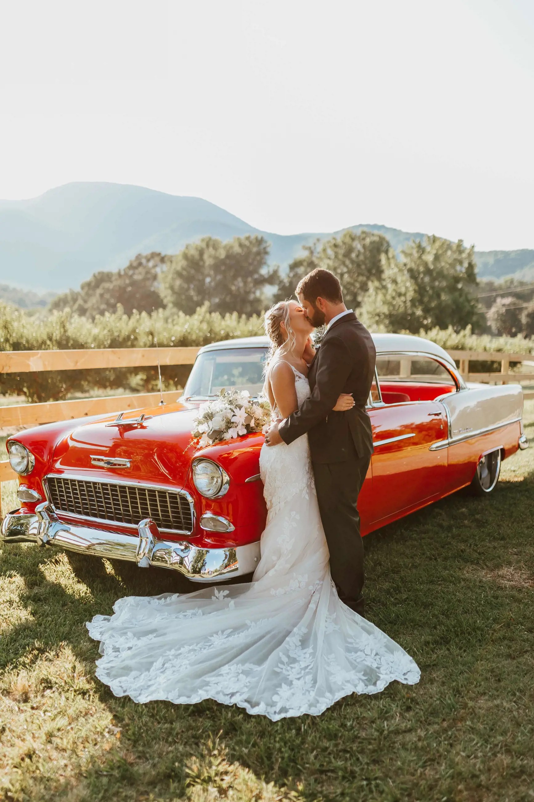 Сouple wearing a white gown and a black suit near the car